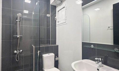 Modern bathroom interior with black tiles, featuring a shower area, toilet, and sink with Auto Draft and a mirror.