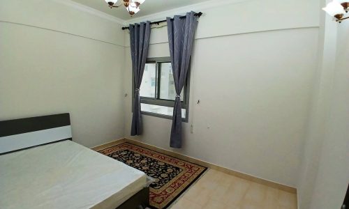 A minimalistic bedroom with a bed, gray curtains, a small rug, wall-mounted lights, and an auto draft system.