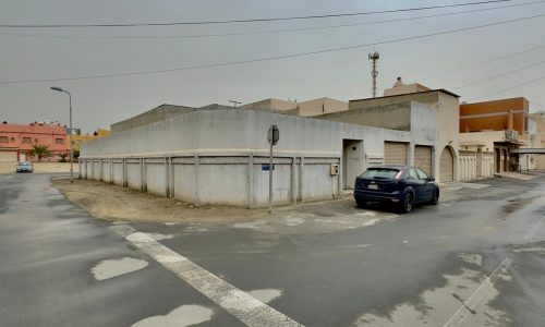 A solitary car parked by a street on an overcast day in an empty industrial area, located on a corner.