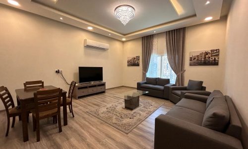 Luxury apartment living room with l-shaped sofa, dining table, and flat-screen tv.