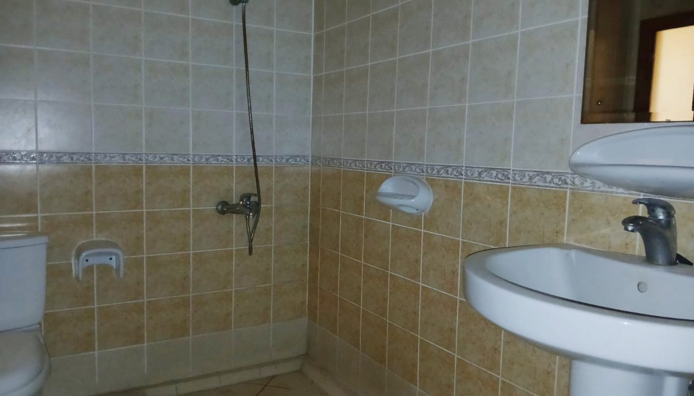 A simple bathroom with beige tiles featuring a shower, toilet, and Auto Draft pedestal sink.