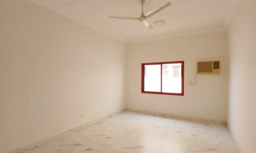 A commercial flat in a prime location, featuring an empty room with white walls, a ceiling fan, marble flooring, and a window with a red frame in Guful.