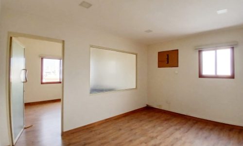 A bright, empty Auto Draft room with hardwood floors, a large mirrored closet door, and two windows.