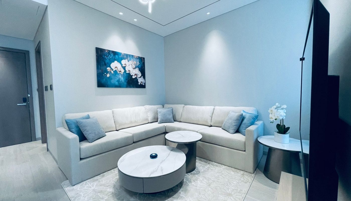 An amazing apartment living room with an L-shaped sofa, a round coffee table, and wall art.