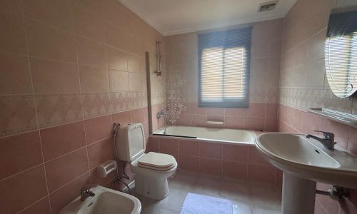 A bathroom with a bathtub, toilet, bidet, and auto draft sink under a window with closed blinds.