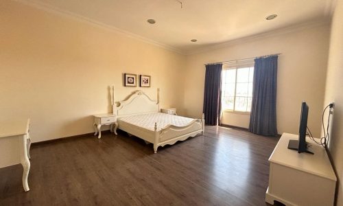 A spacious, well-lit bedroom in a Fully-Furnished Villa with classic furniture and hardwood floors.