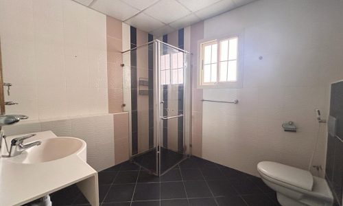 Public restroom in a fully-furnished 3 BDR Villa in the Saar Area, with a glass shower stall, sink, and toilet.