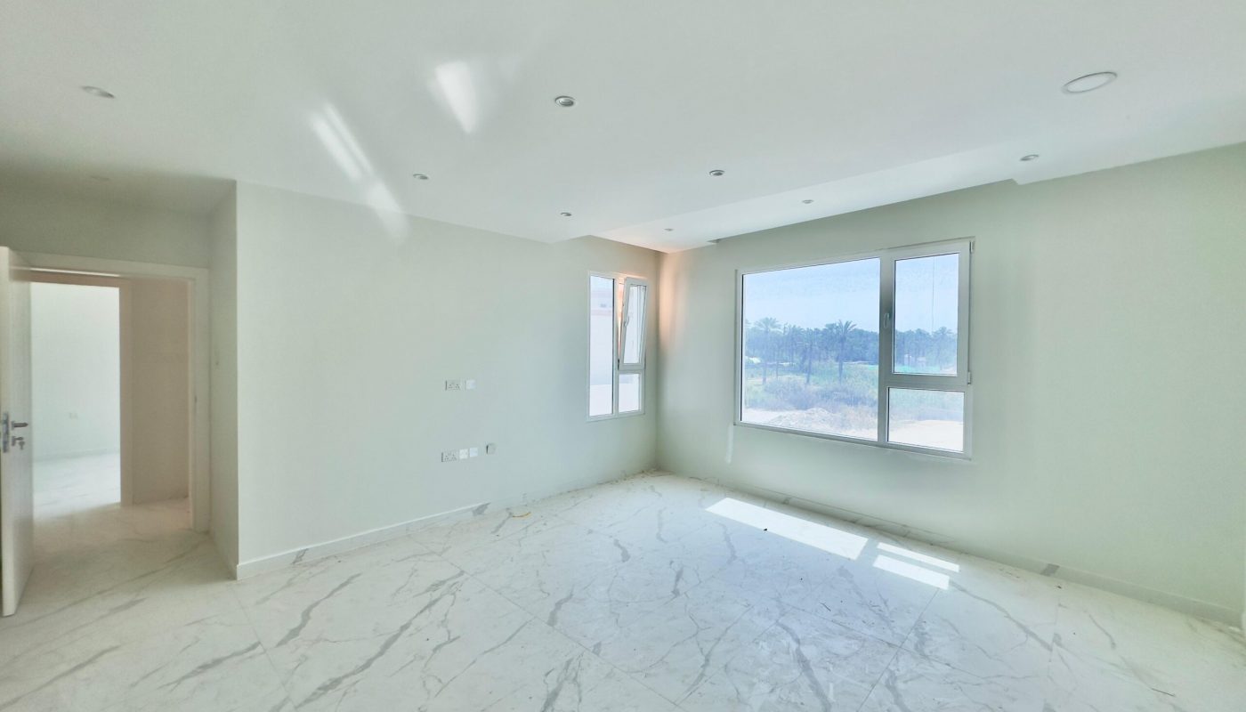 Bright, empty room with white marble flooring, multiple windows, and recessed ceiling lights. view of greenery outside.