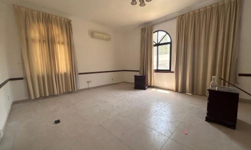 Empty room with cream curtains, tiled floor, and vintage furniture at the corners under a chandelier and air conditioner, optimized for SEO keywords.