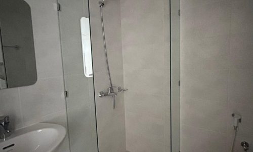 A small, modern bathroom with a glass shower stall, white sink, and an auto draft mirrored cabinet.