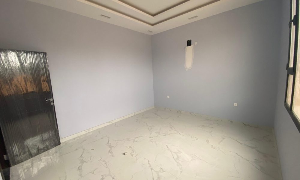 An elegant villa room with light gray walls, a large window on the right, a black-framed door on the left, and a white tiled floor with a subtle marble pattern reflects the refined aesthetics of the Danat Hidd scheme.