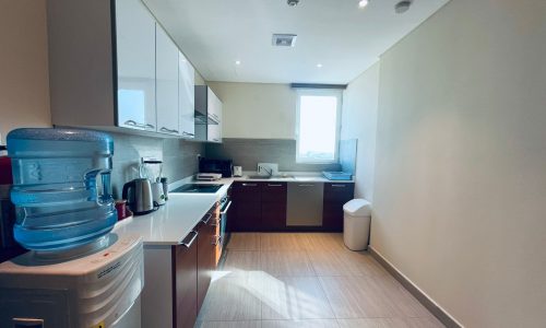 Modern kitchen interior with stainless steel appliances, wooden cabinets, and a large window letting in natural light.