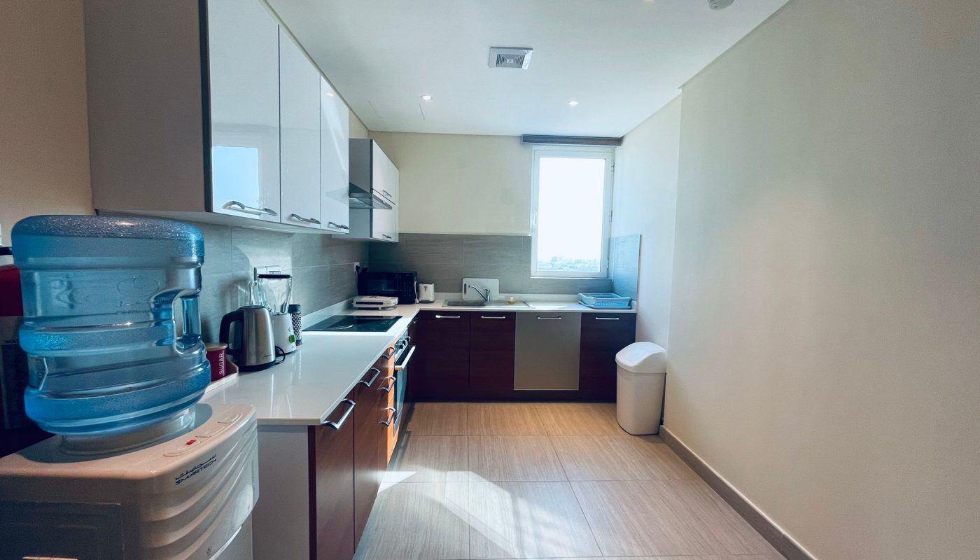 Modern kitchen interior with stainless steel appliances, wooden cabinets, and a large window letting in natural light.