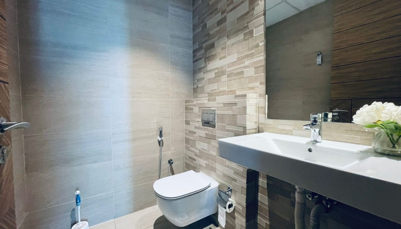 Modern bathroom interior featuring a wall-mounted toilet, sink, and a mix of wooden and tiled walls, with auto draft and subtle lighting.