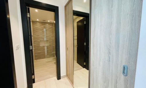 Modern home interior hallway in the stylish Al-Burhama area featuring multiple open doors with various finishes, including a glimpse of a bathroom.