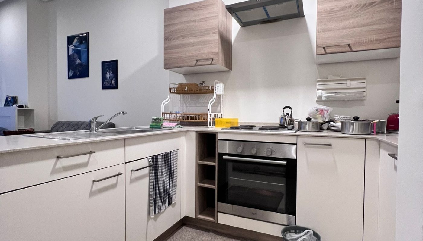 A modern kitchen with white cabinets, wooden accents, built-in appliances, and a tile floor, showcasing a clean and organized interior.