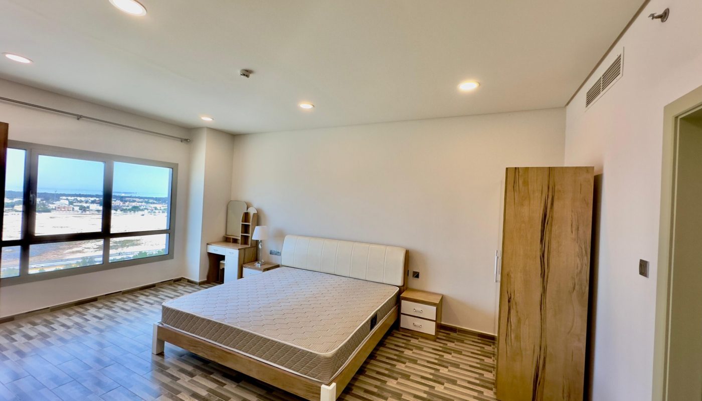 A luxury apartment bedroom with a large bed, herringbone floor, wardrobe, and ceiling lights, featuring a wide window with a city view.