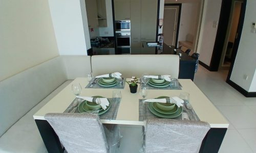 Modern dining room with a table set for four, kitchen in the background, and chairs covered in Auto Draft plastic.