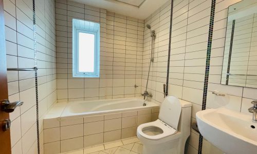 Luxury apartment bathroom with a white bathtub, toilet, and sink, tiled walls, and a small window letting in natural light.