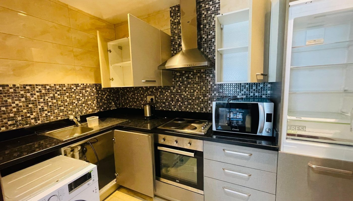 Modern kitchen with stainless steel appliances, mosaic tile backsplash, and a combination of dark countertops and grey cabinets.