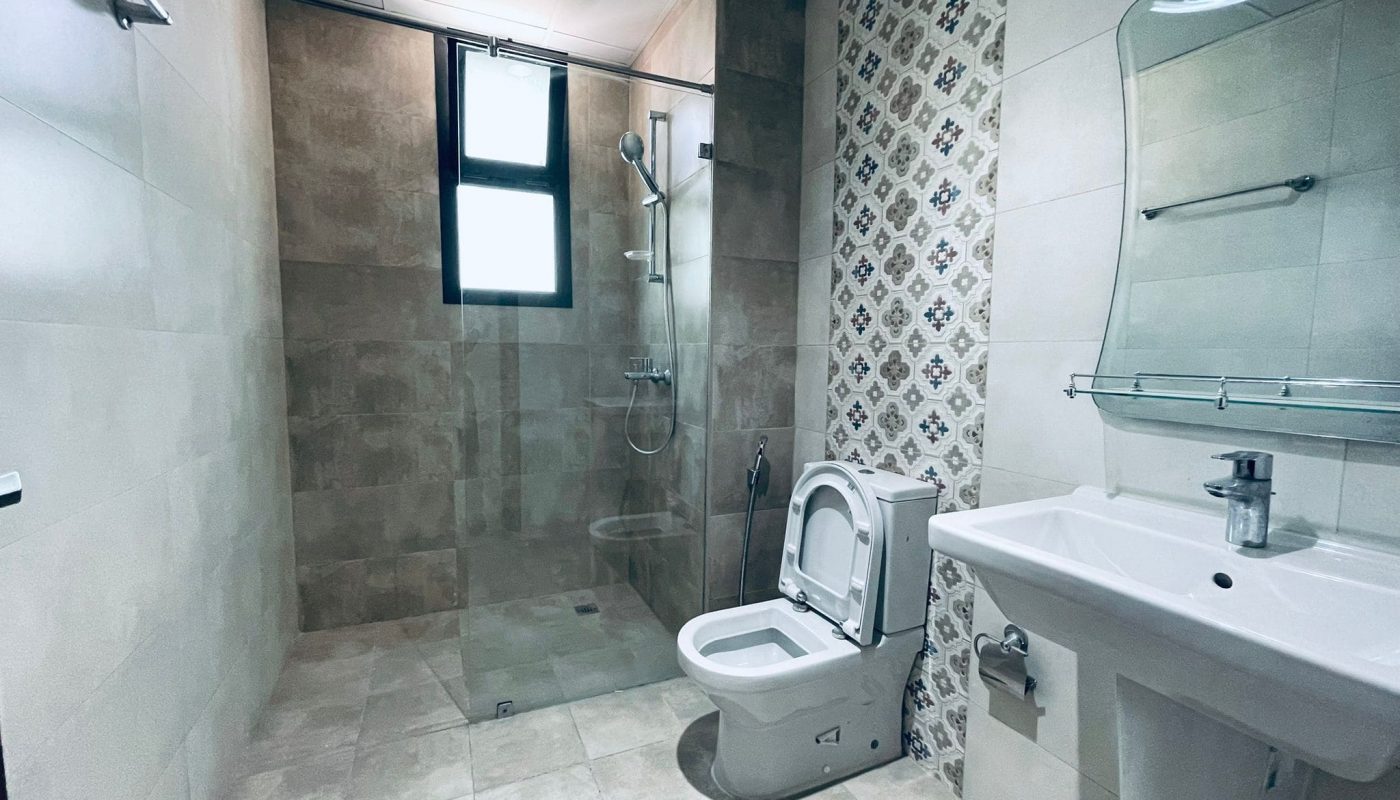 Modern luxury bathroom interior featuring a toilet, sink, and a walk-in shower with glass partition.