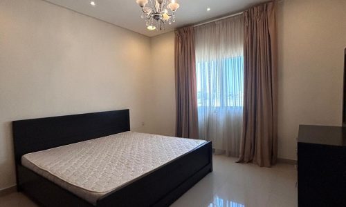 A modern bedroom featuring a king-sized bed, glossy floor, a chandelier, recessed lighting, and large window with curtains.