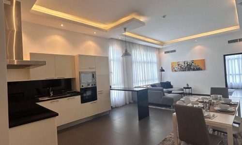 Luxury open-plan apartment interior with a kitchen, dining area, and living room, featuring neutral colors and contemporary furnishings.