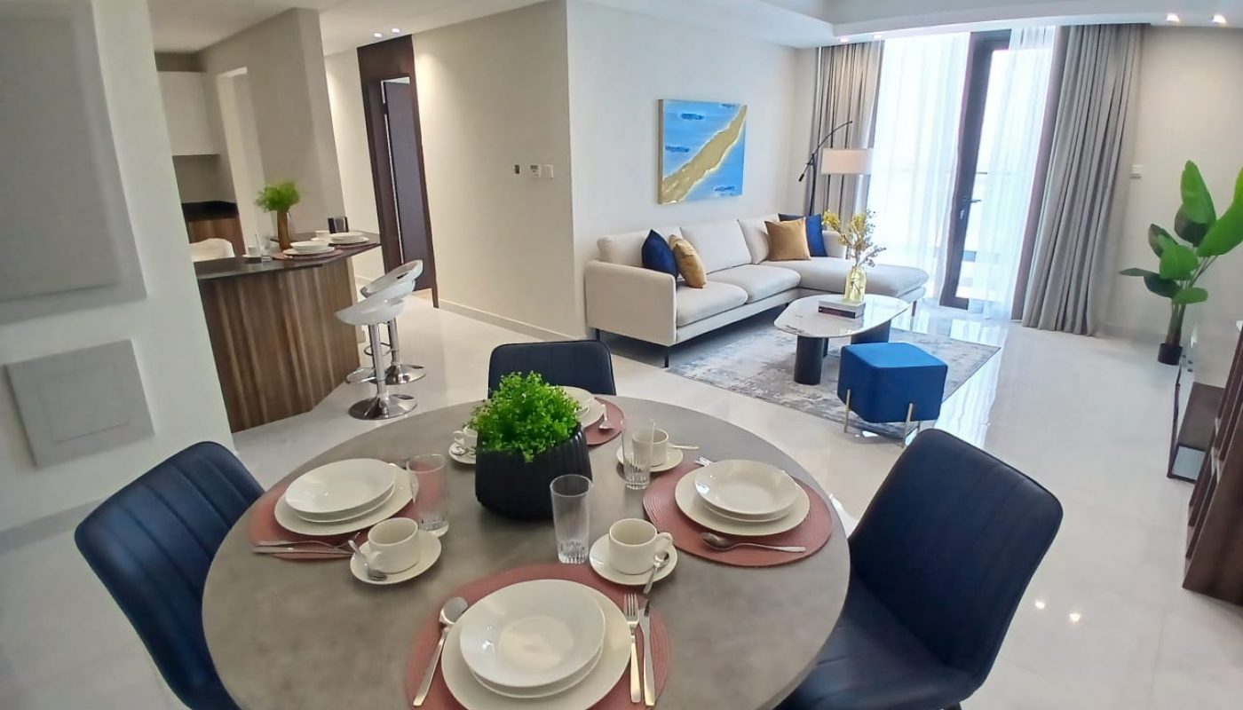 Modern open-plan living and dining area with a set dining table, sofa, armchairs, large window, and contemporary decor.