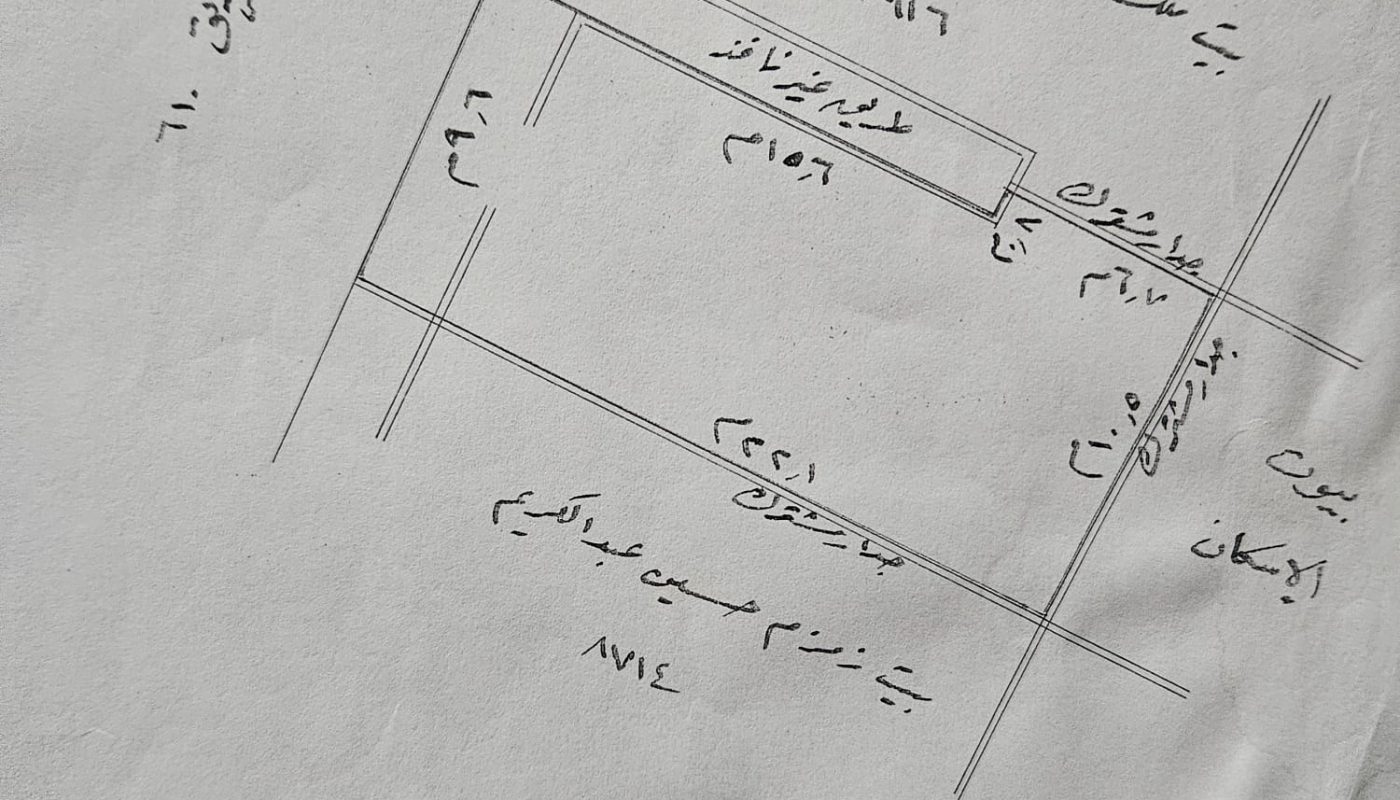 Hand-drawn map with Arabic annotations, showing streets and plot divisions. Dated at the bottom in Arabic and includes handwritten notes on locations.