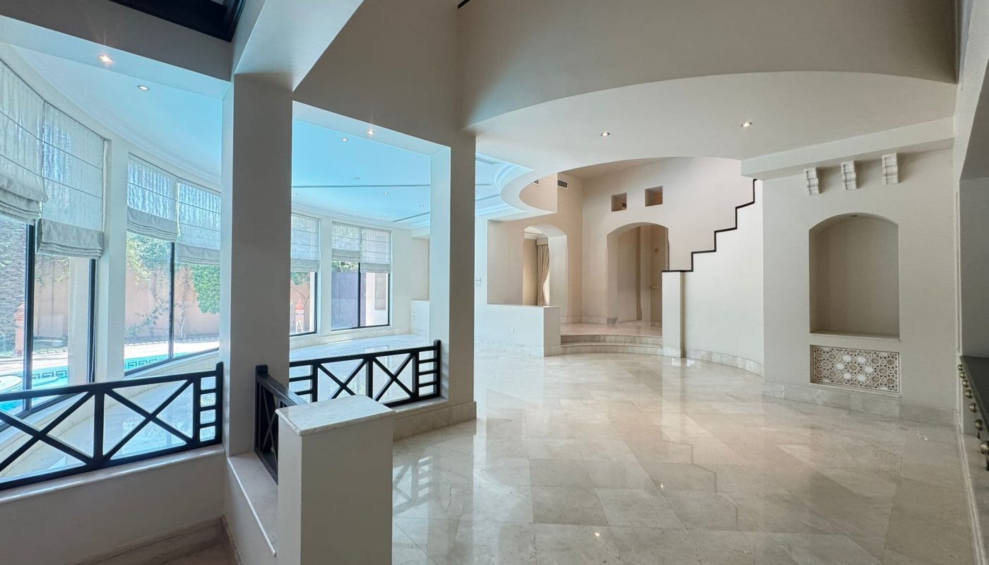Spacious, modern interior with marble floors, large windows overlooking a pool, curved staircase, and minimalist architectural details.