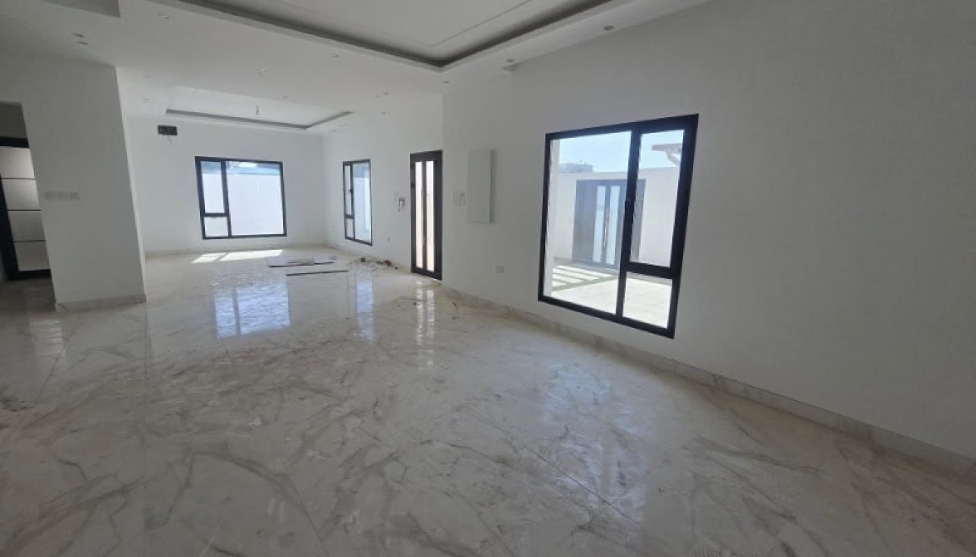 Unfurnished, sunlit room with marble floors, white walls, multiple windows, and a glass door opening to an outdoor area.