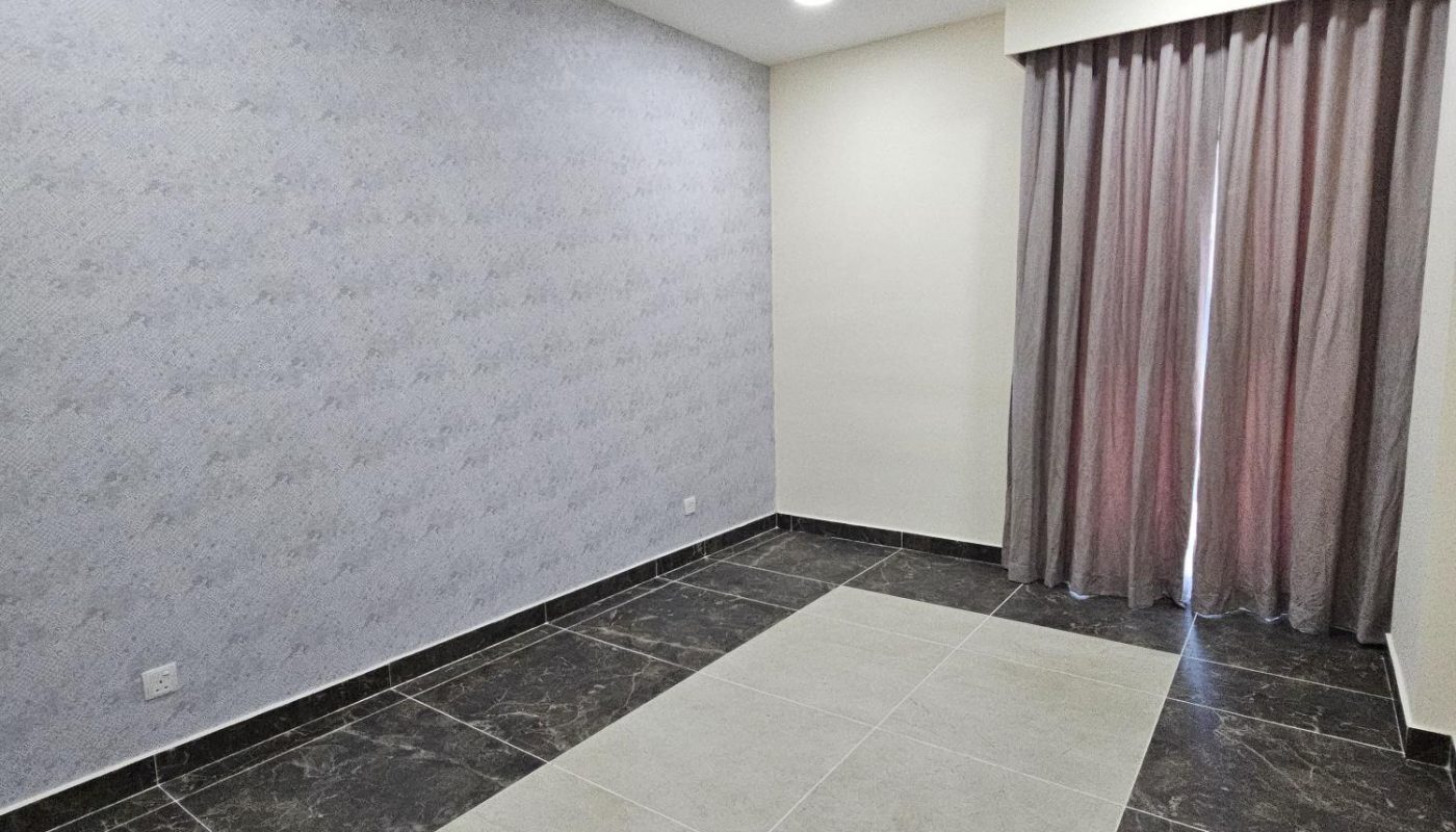 Empty room with patterned tile flooring, one light patterned accent wall, two solid-colored walls, and a window covered by floor-length curtains. Ceiling lights are turned on.