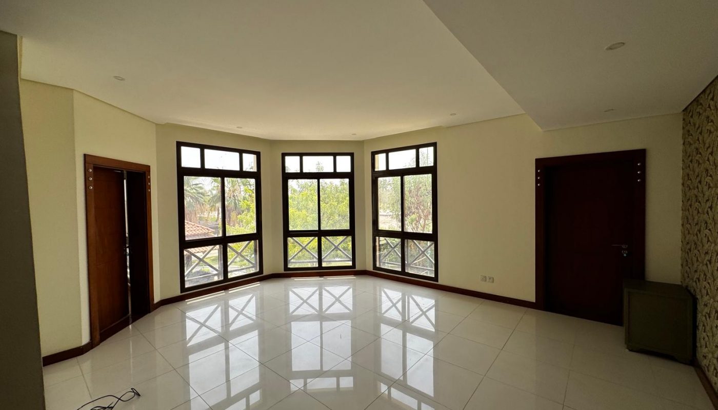 Unfurnished room with large windows, tiled floor, two wooden doors, a small cabinet, and visible electrical cords on the floor.
