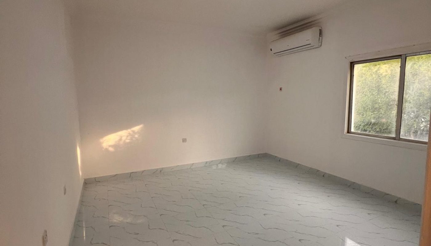 Empty room with white walls, tiled floor, ceiling light, wall-mounted air conditioner, and a window letting in daylight.