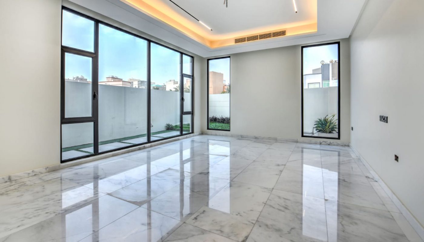 Modern empty room with large marble tile flooring, floor-to-ceiling windows, recessed ceiling lighting, and white walls.