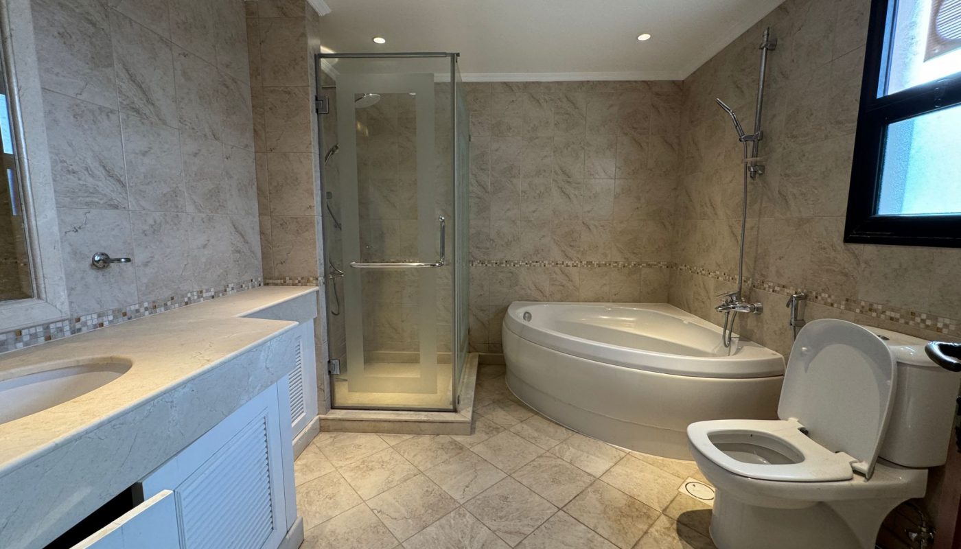 Modern bathroom with a glass-enclosed shower, corner bathtub, toilet, double sink vanity, and tiled walls and floors.