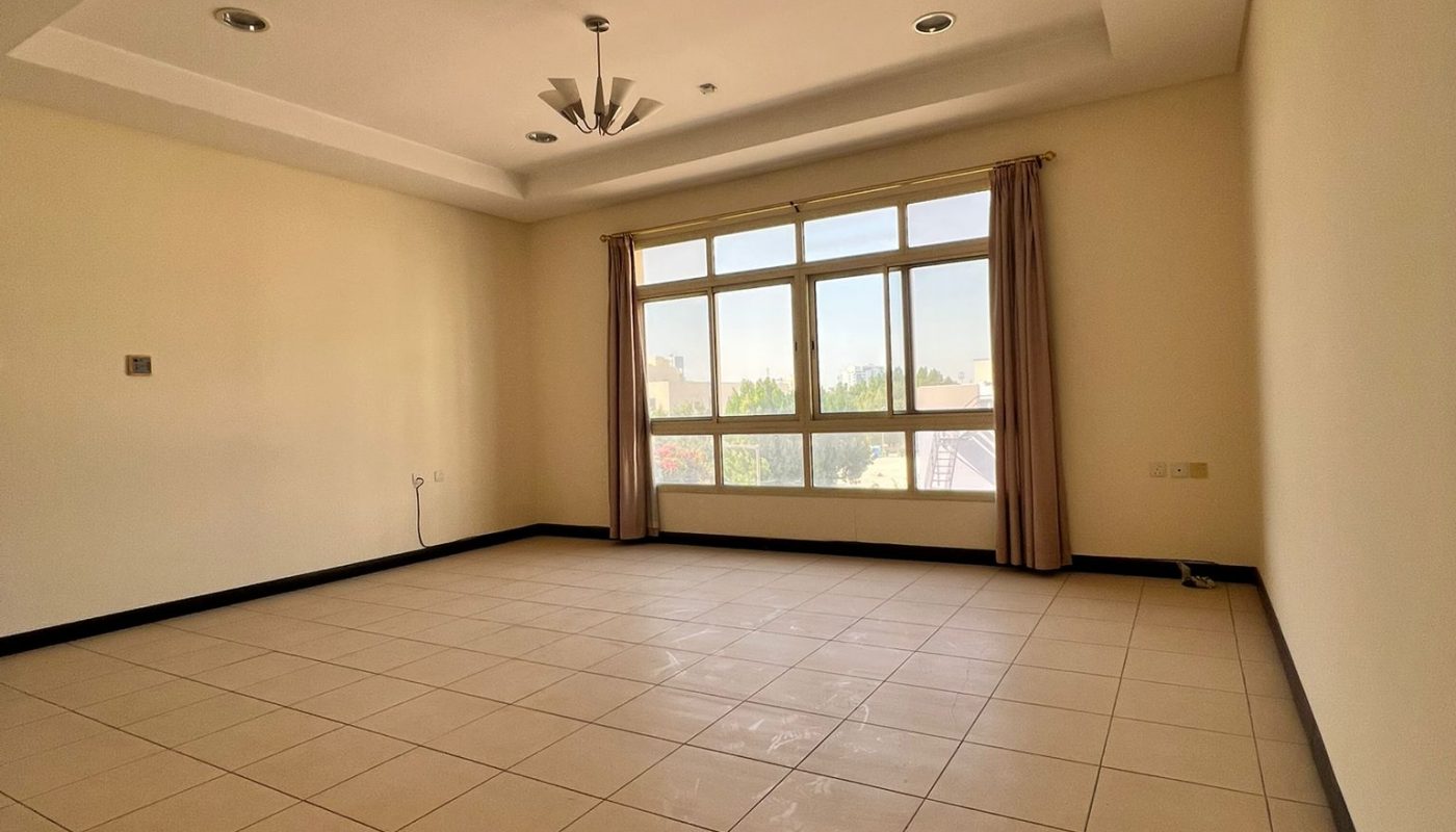 Empty room with beige tiled floor, cream-colored walls, ceiling fan, recessed lighting, large windows, and tan curtains letting in natural light.