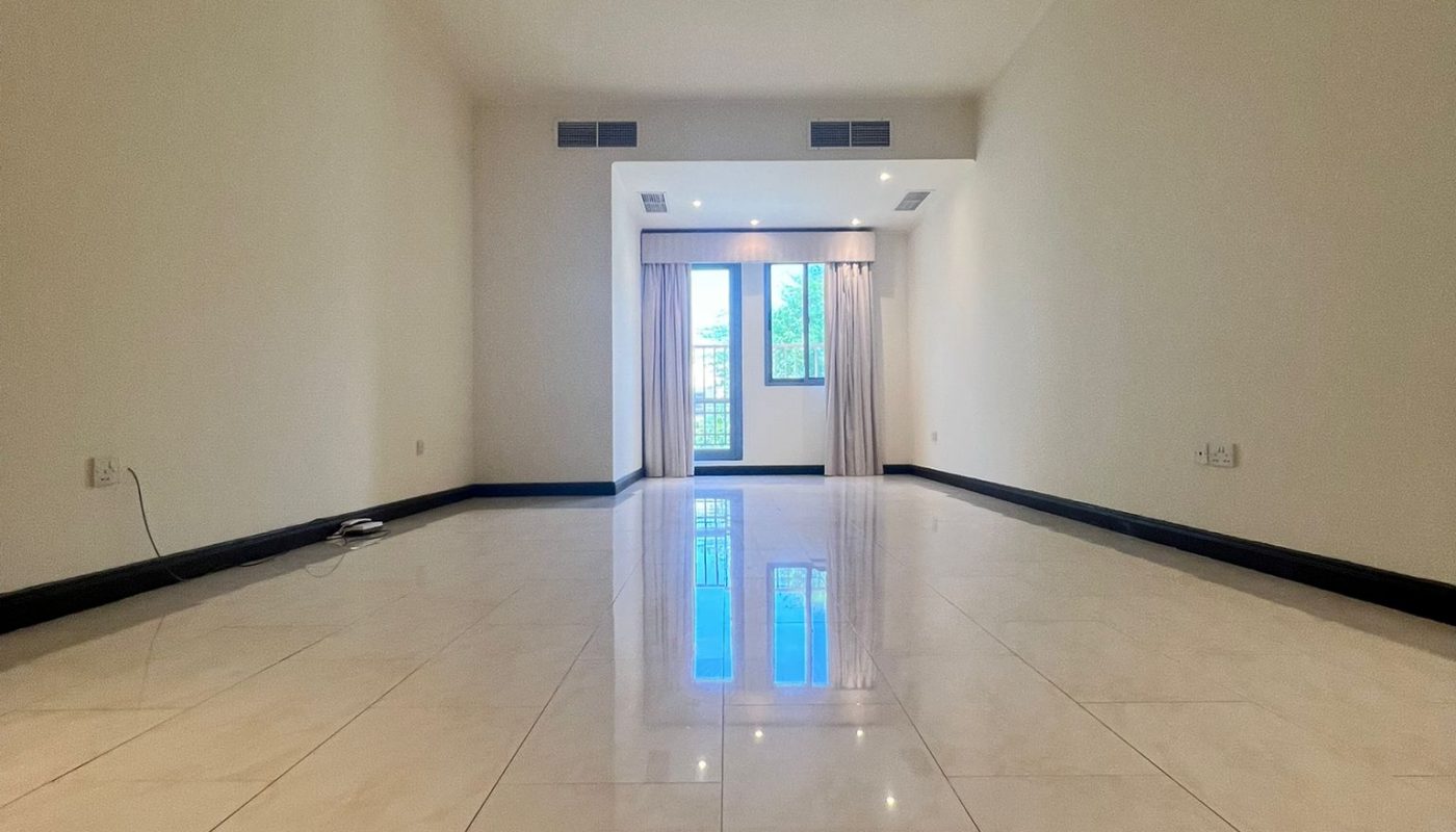 Empty room with white tiled floor, plain light-colored walls, and a large window at the far end with curtains partially drawn.