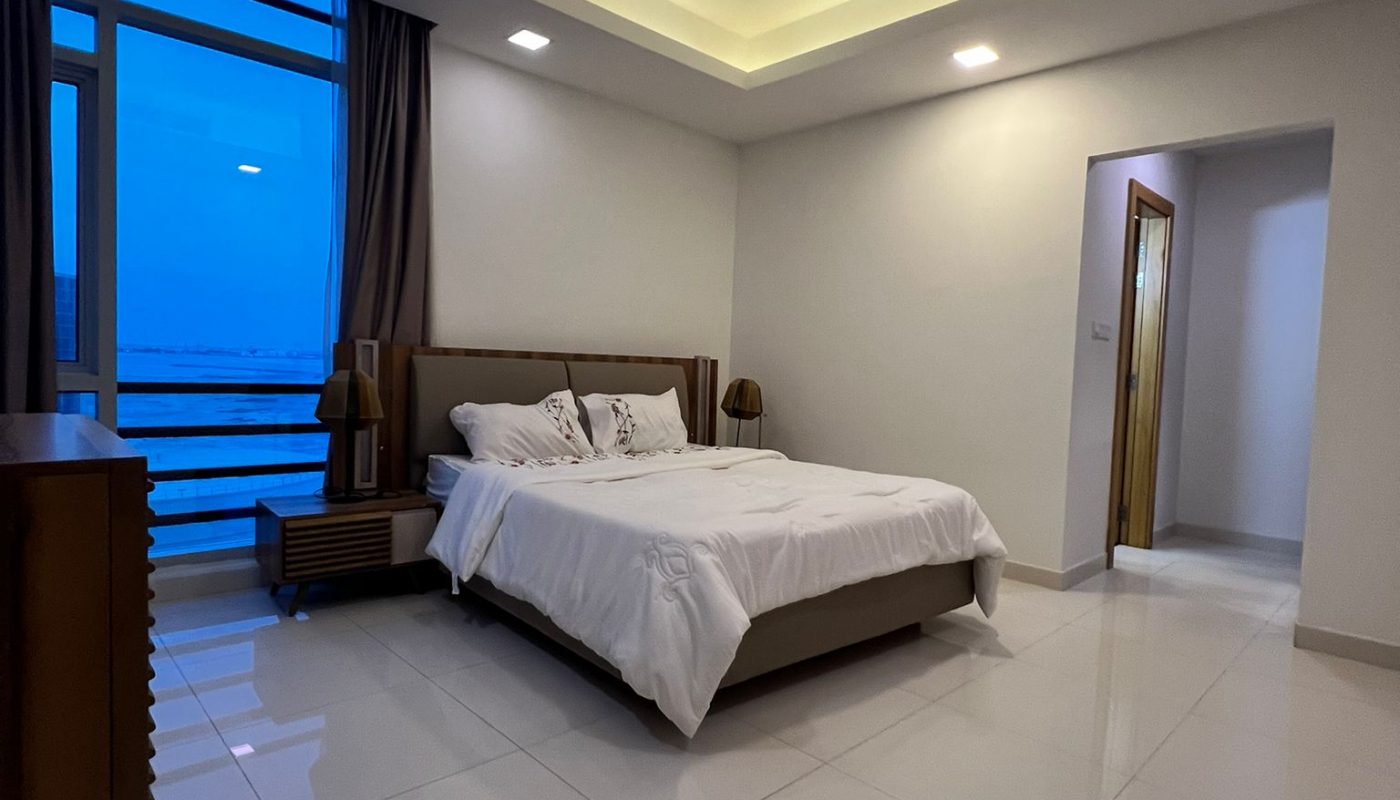 Modern bedroom with a double bed, bedside tables, dresser, large window with curtain, and tiled floors under recessed ceiling lights.