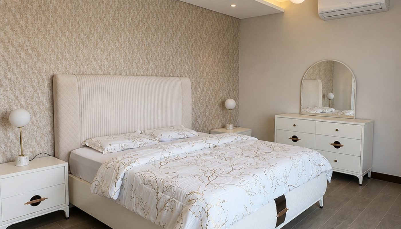Modern bedroom with a double bed, two nightstands, a dresser with a round mirror, wood-look flooring, and a contemporary ceiling light fixture.