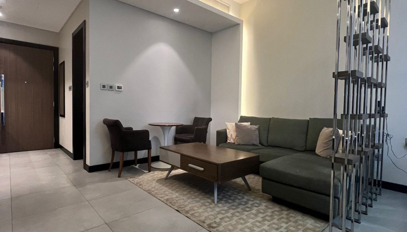 Modern living room with gray sectional sofa, wooden coffee table, two chairs and a small table, large tiled floor, and a metal divider separating areas.