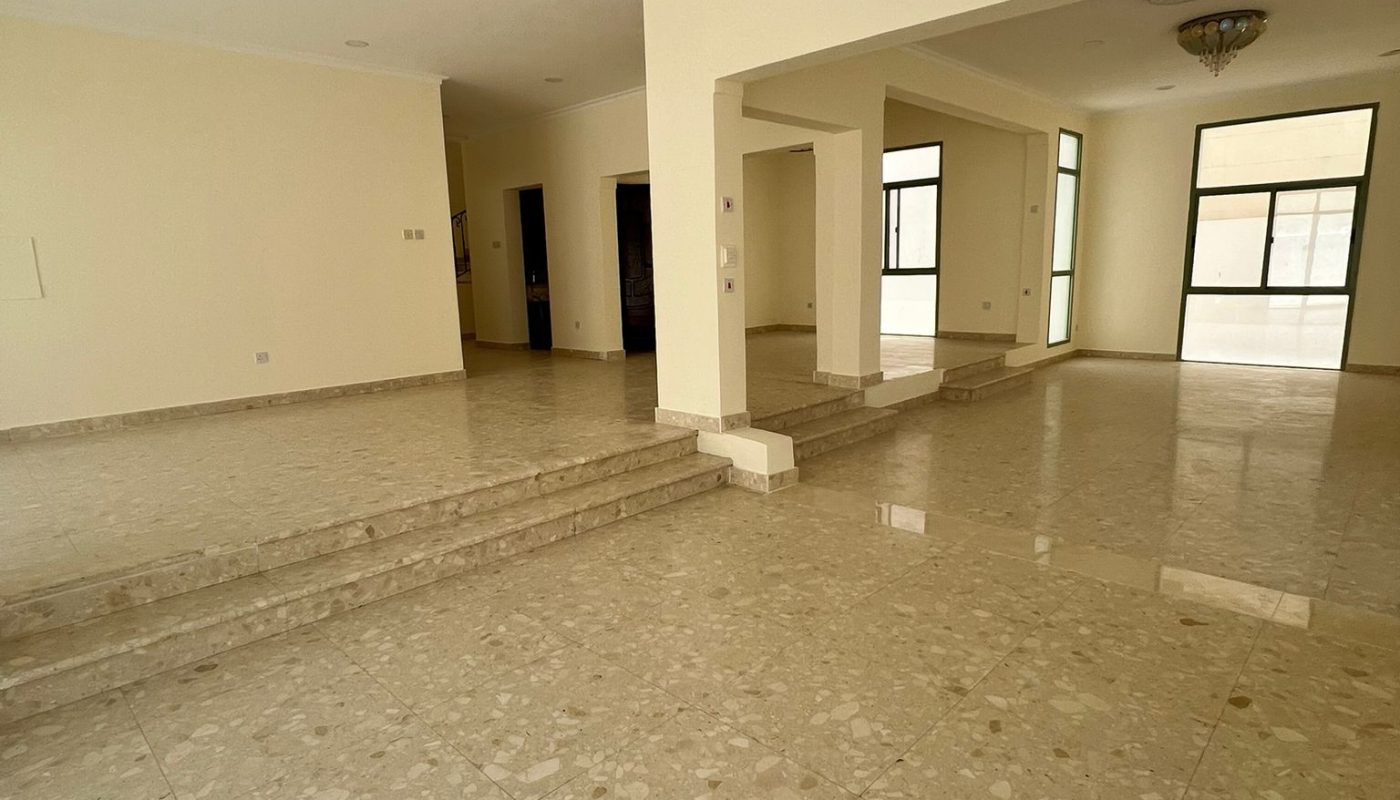 Spacious empty room with marble floors, cream-colored walls, large windows, and multiple steps leading to different floor levels.
