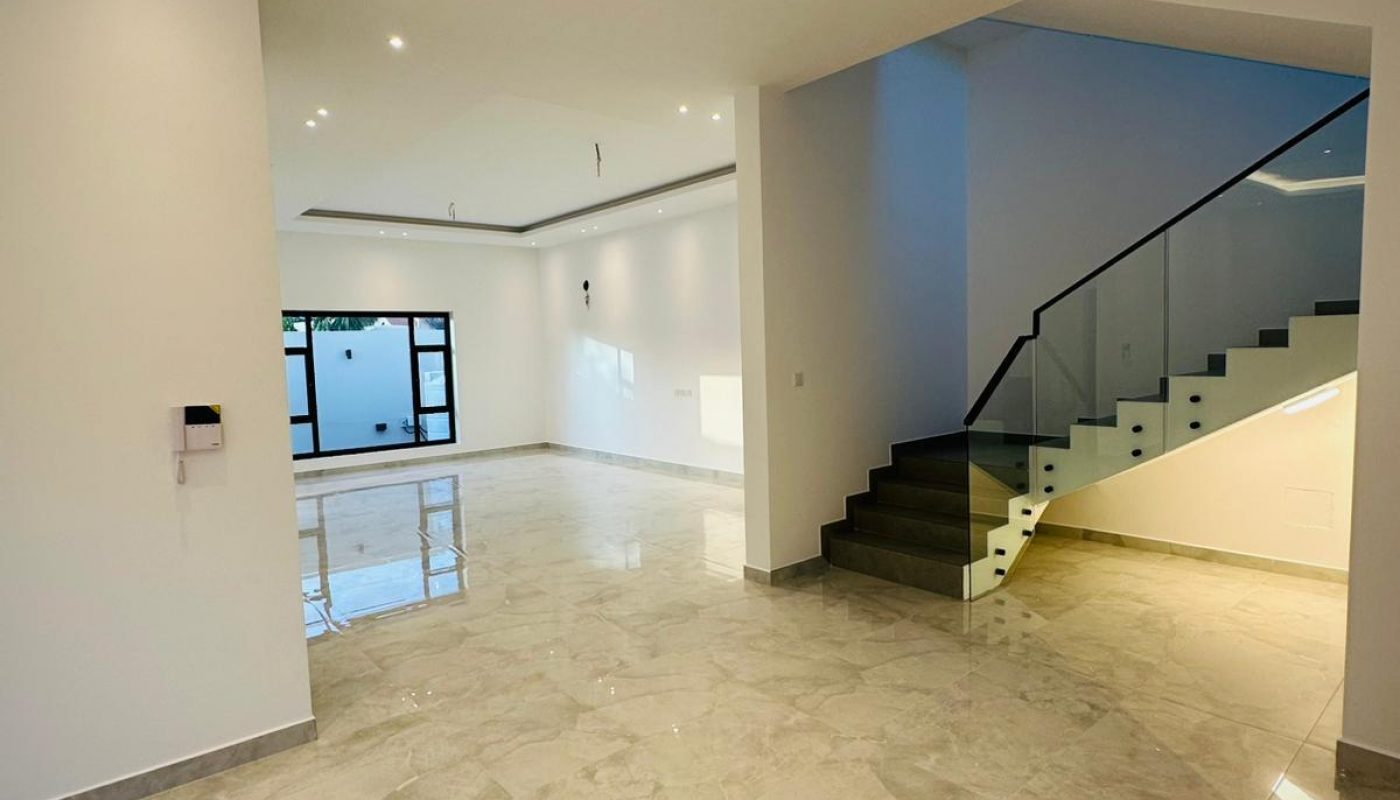 A modern interior with a marble-tiled floor, white walls, and a glass-railed staircase.