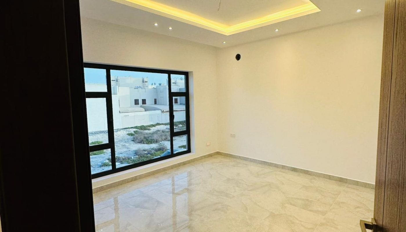 Empty room with tiled floor, large window, and modern ceiling lighting.