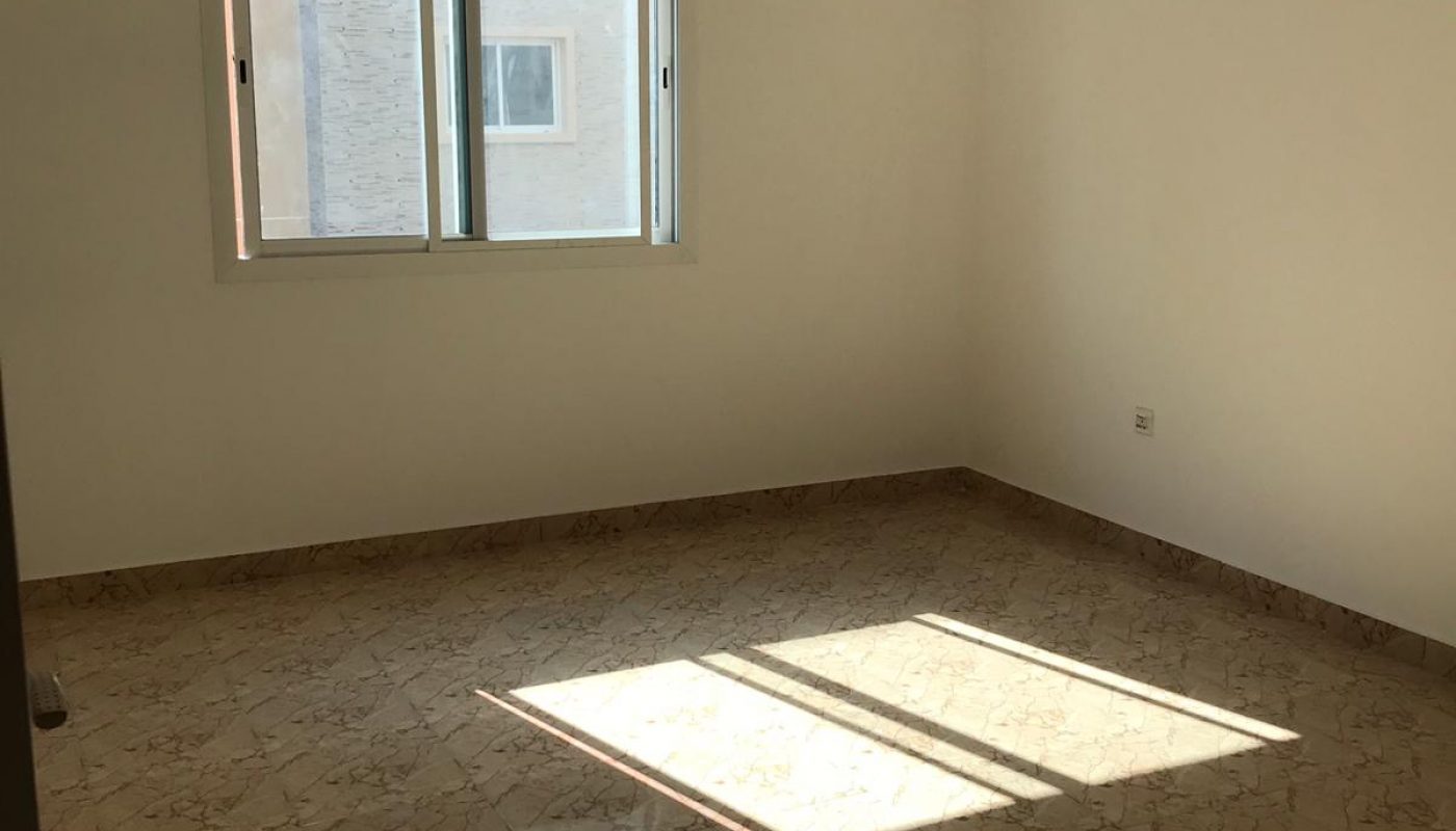 Empty room with marble tile floor, cream-colored walls, a window with sunlight streaming in, a ceiling fan, and a wall-mounted light fixture.