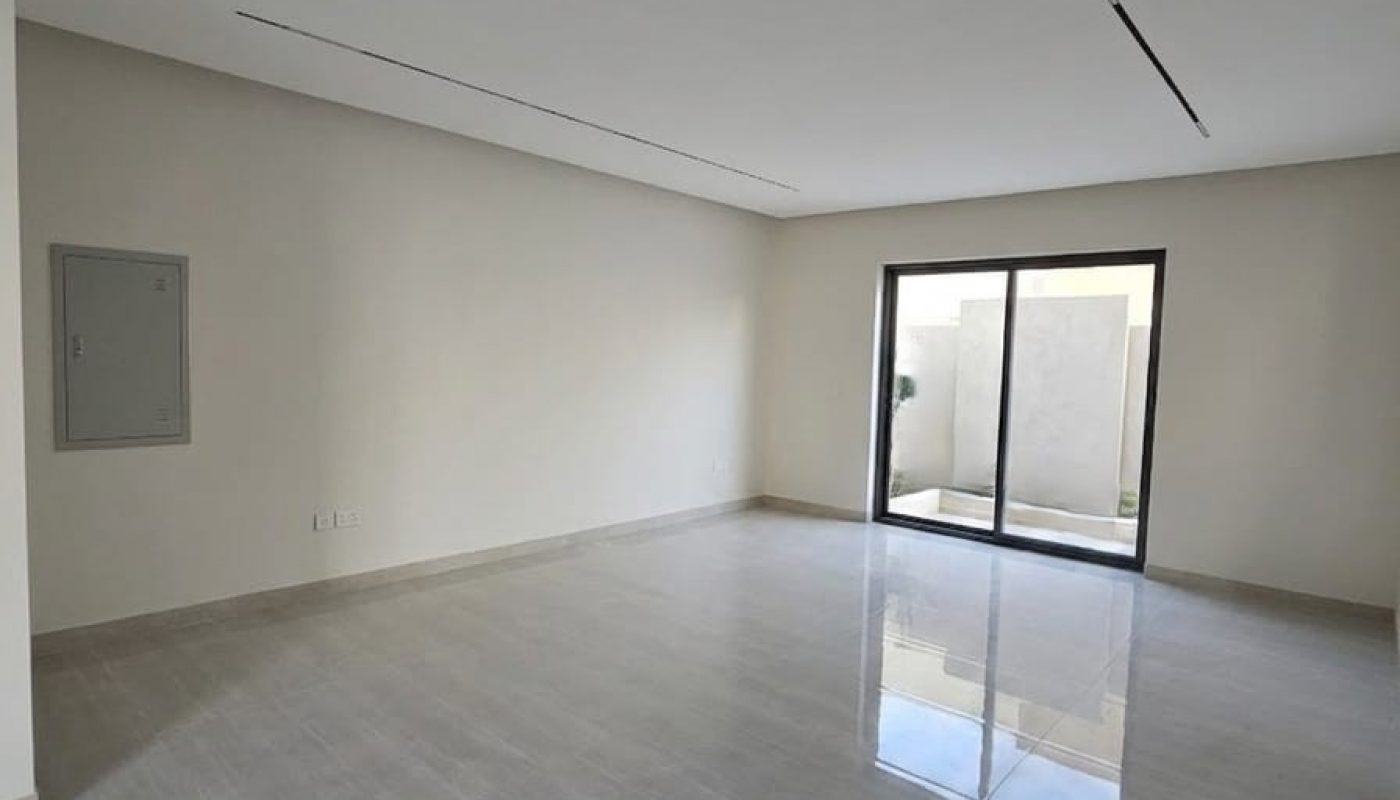 Empty room with light gray tiled floor, white walls, a sliding glass door leading outside, and a small utility panel on the left wall.