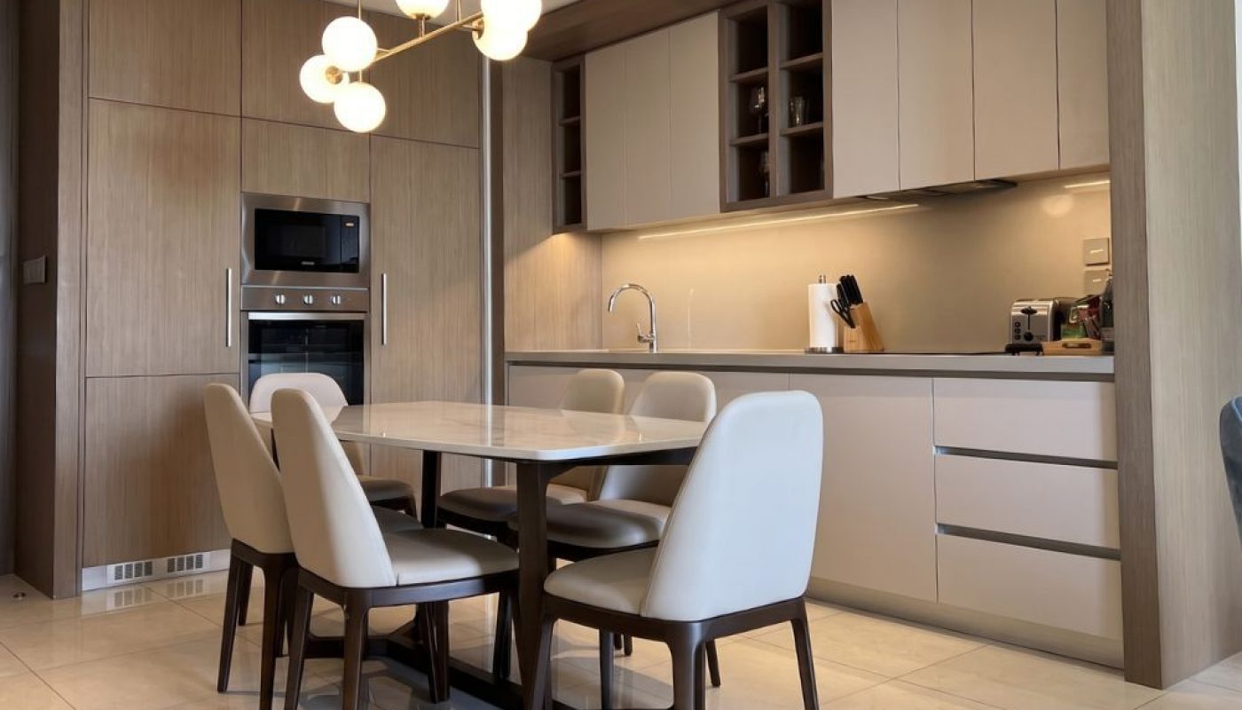 Modern kitchen and dining area with a table and six chairs, built-in appliances, minimalist cabinets, and a contemporary light fixture.