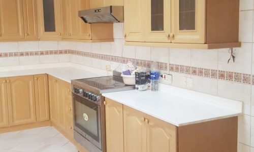 A furnished kitchen in a villa with beige cabinets and tiled floors available for rent.