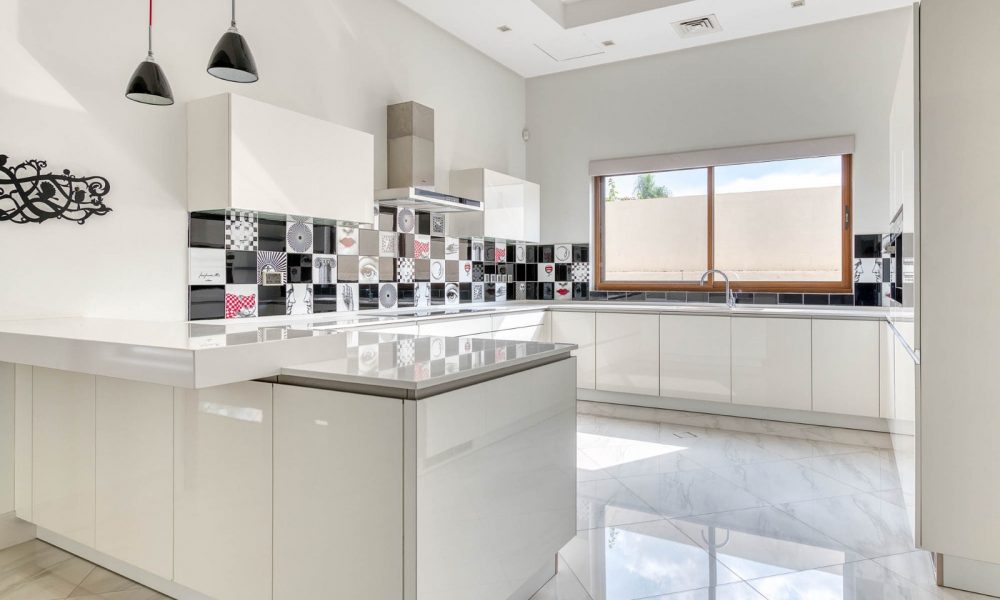 Stunning white kitchen with a black and white tiled floor.