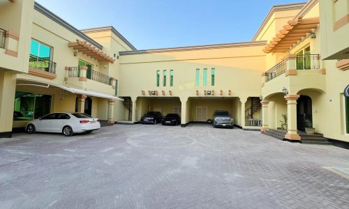 A building with cars parked in front of it, serving as an auto dealership.